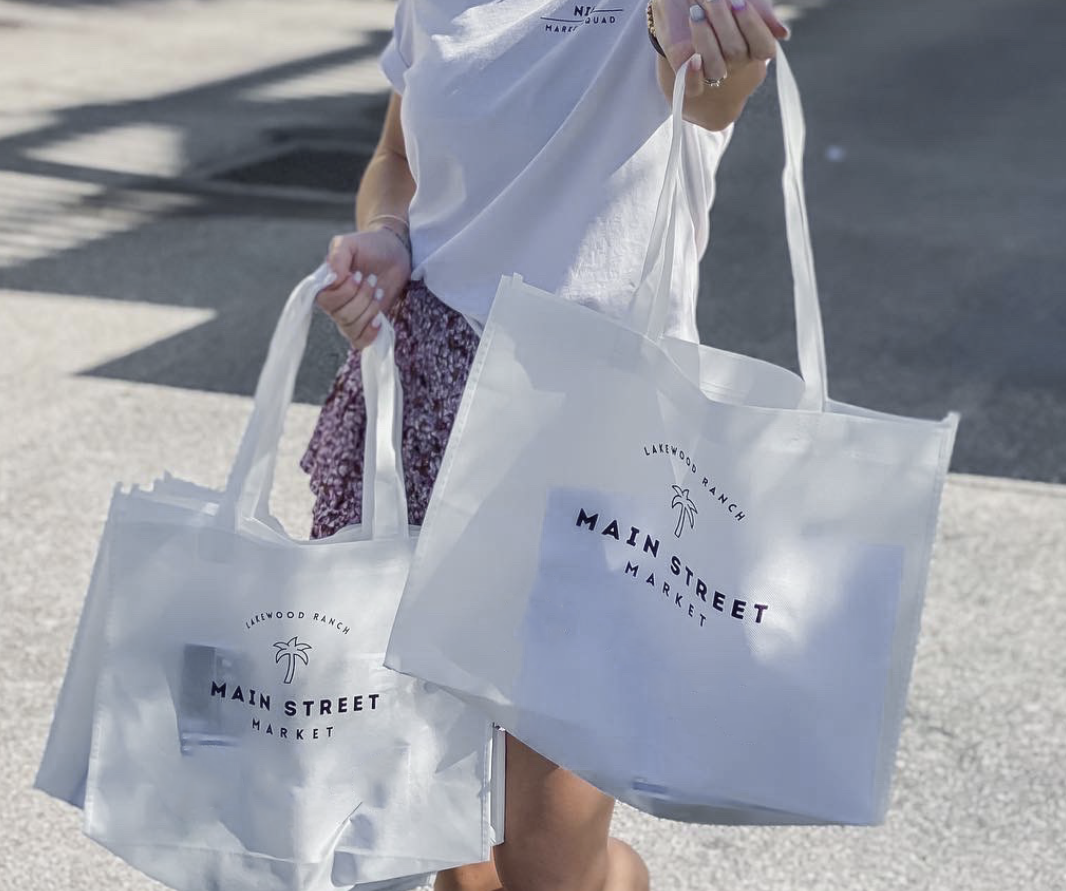 person holding 2 reusable Main Street Market Lakewood Ranch bags